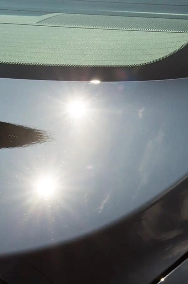 Gray hood after paint correction, with sharp sun reflections